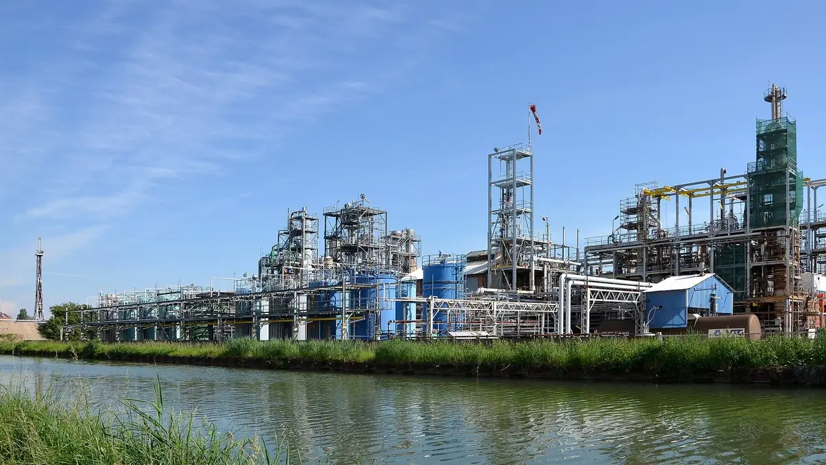 Heavy-industry chemical plant with process units and columns beside a canal