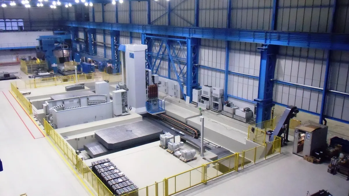 Large industrial manufacturing hall with heavy machining equipment and crane runway
