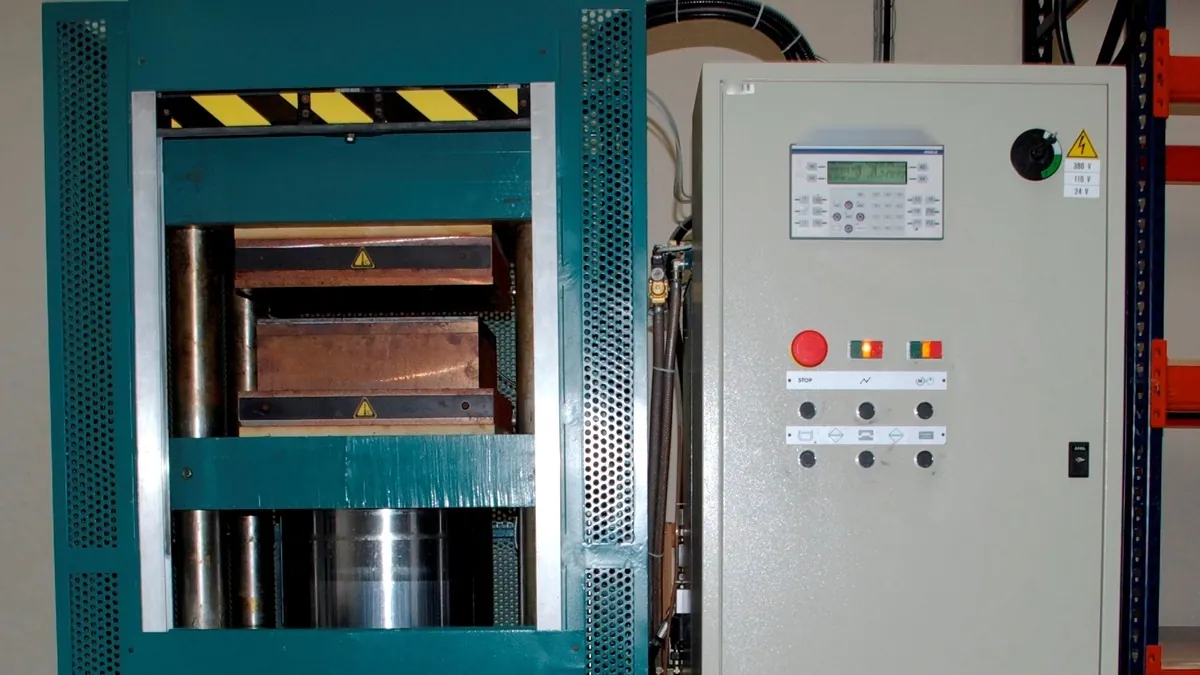 Industrial hydraulic hot press with heated platens and control cabinet, the type of press used to laminate cell components