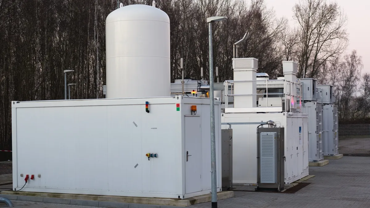 Hydrogen pilot plant on a test site with process containers, coolers and a vertical storage tank