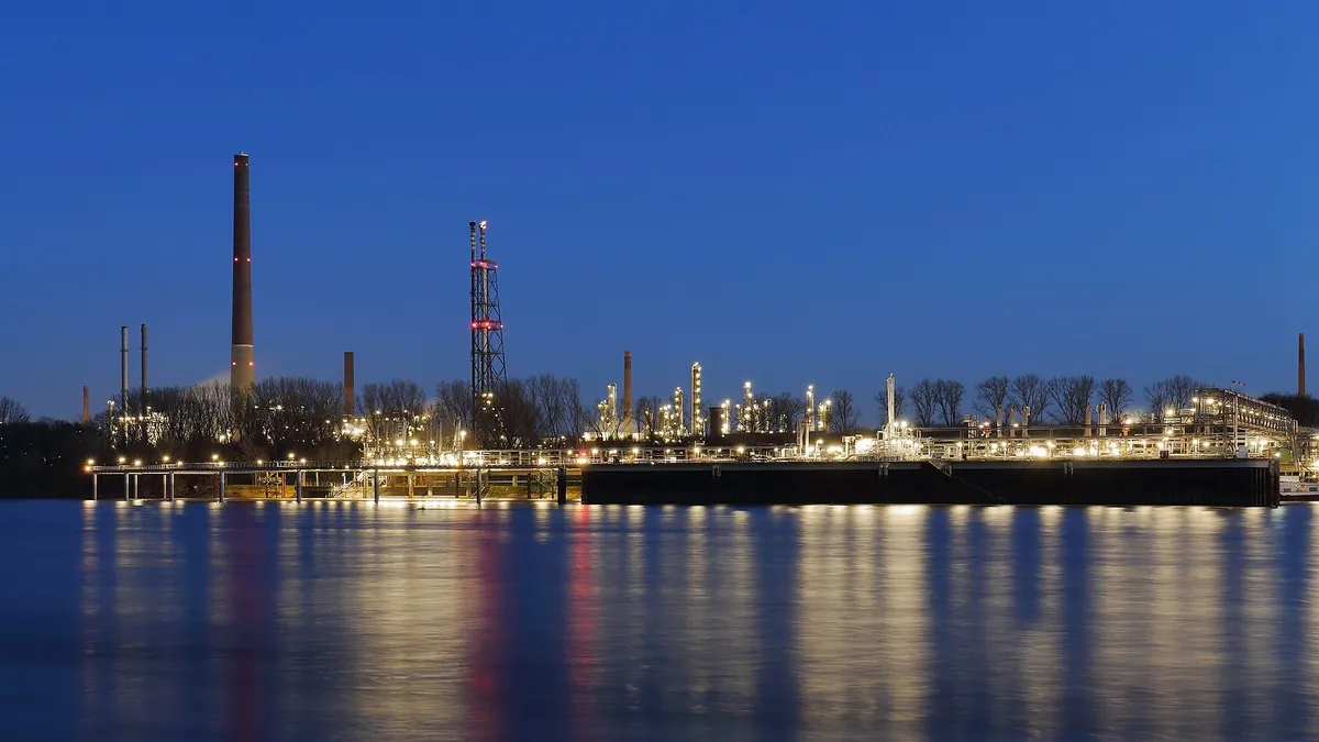 Refinery illuminated at dusk across the river, a typical large-volume hydrogen offtaker