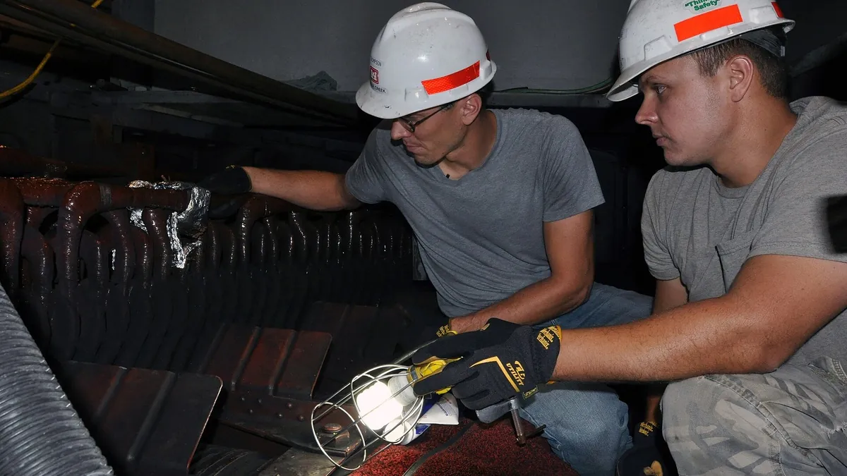 Technicians in hard hats carrying out a repair on industrial plant equipment