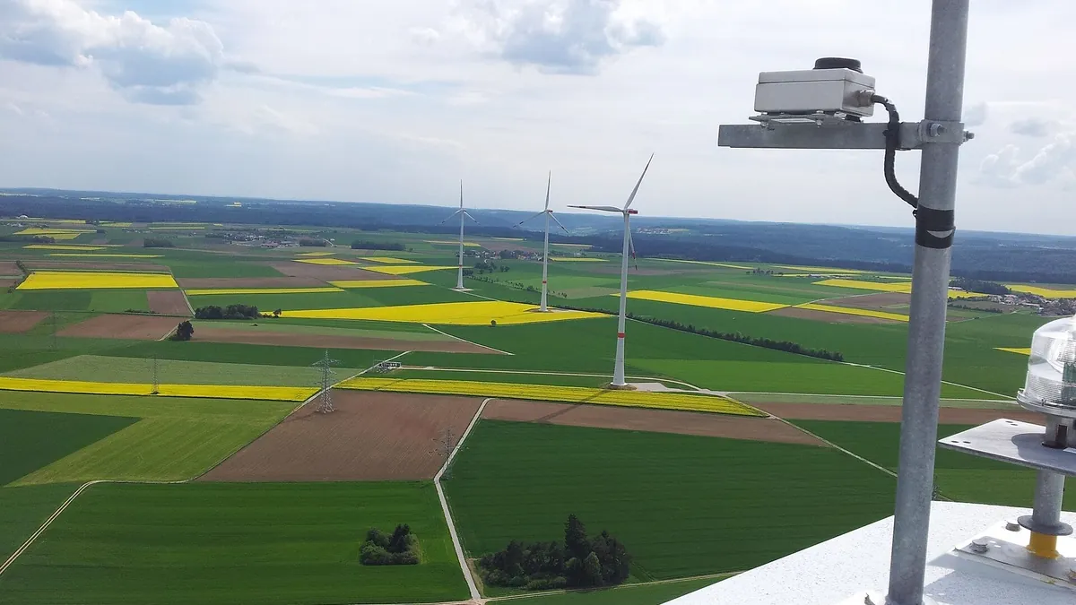 Wind farm with grid connection seen from a metering mast, the traceable renewable supply behind guarantees of origin