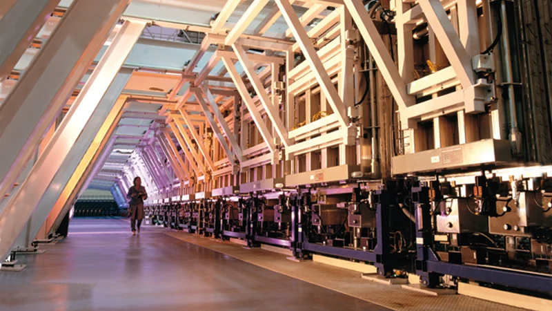 Long roll-to-roll production line in an industrial hall, symbolising scale-up of electrode manufacturing.