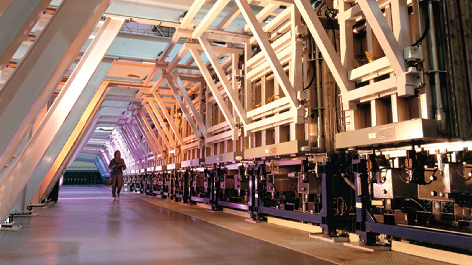 Long roll-to-roll production line in an industrial hall, symbolising scale-up of electrode manufacturing.
